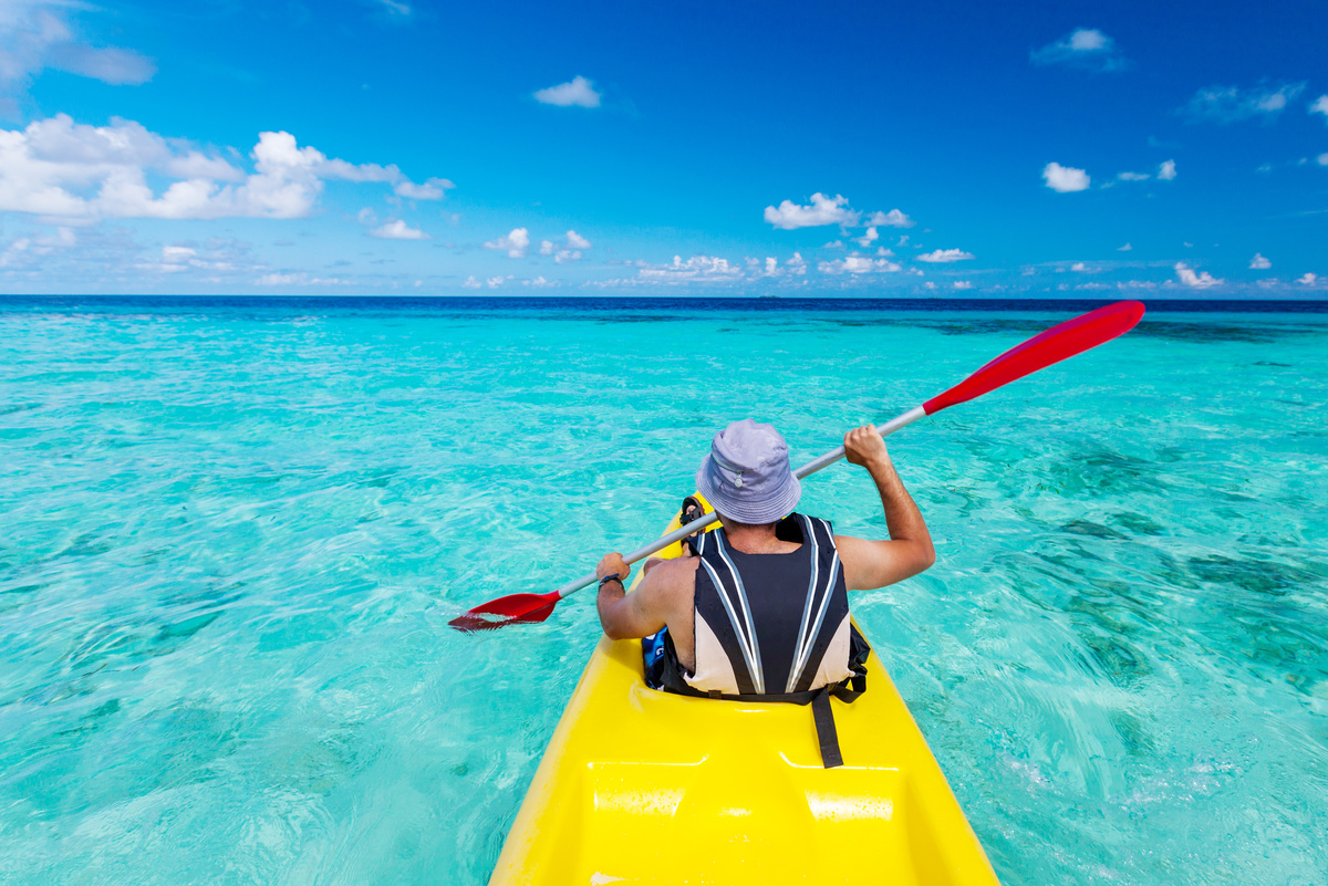 Young caucasian man kayaking in sea at Maldives